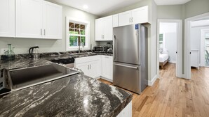 A modern kitchen with white cabinets, a stainless steel refrigerator, and a black marble countertop. - Union Pier Cottage Close To Everything! One Of Three Units! (Union Pier)