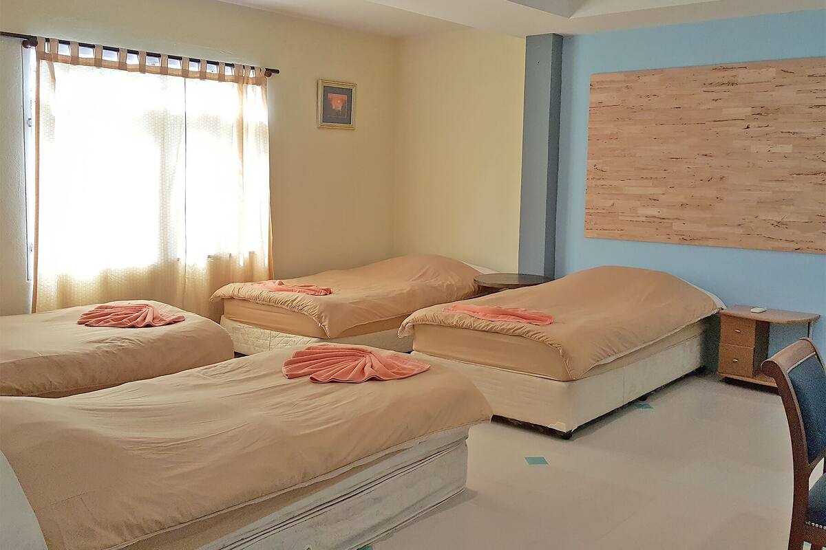 Ein Zimmer mit zwei Einzelbetten, einem kleinen runden Tisch und einer Holzverkleidung an der Wand.