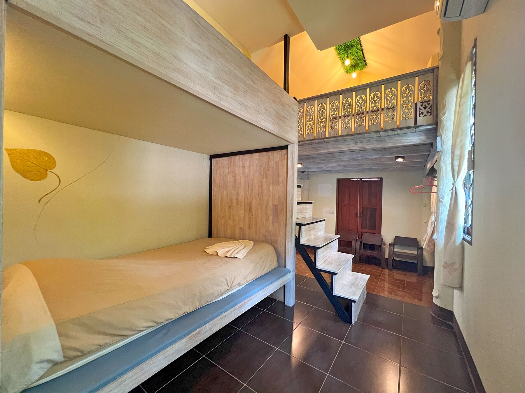 A compact room with a bunk bed, a staircase, and a decorative wall.