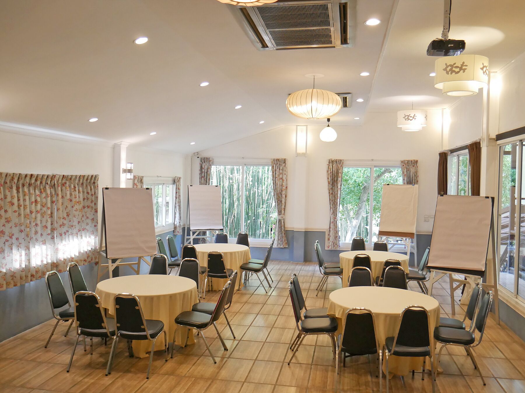 Un salón de conferencias con mesas redondas, sillas y pizarras blancas.