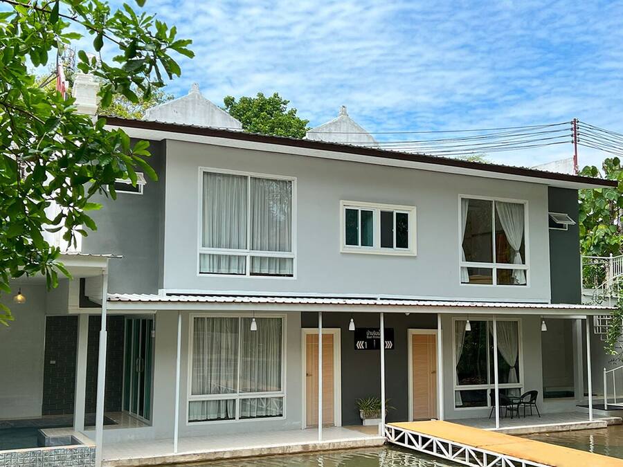 A two-story house with a balcony, a swimming pool, and a small dock.