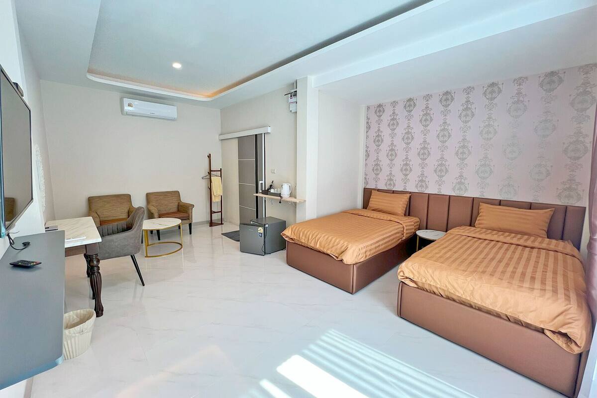 Ein modernes Hotelzimmer mit zwei Betten, einem Schreibtisch, einem Stuhl und einem kleinen Tisch.