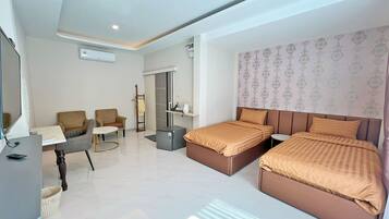 A modern hotel room with two beds, a desk, a chair, and a small table.