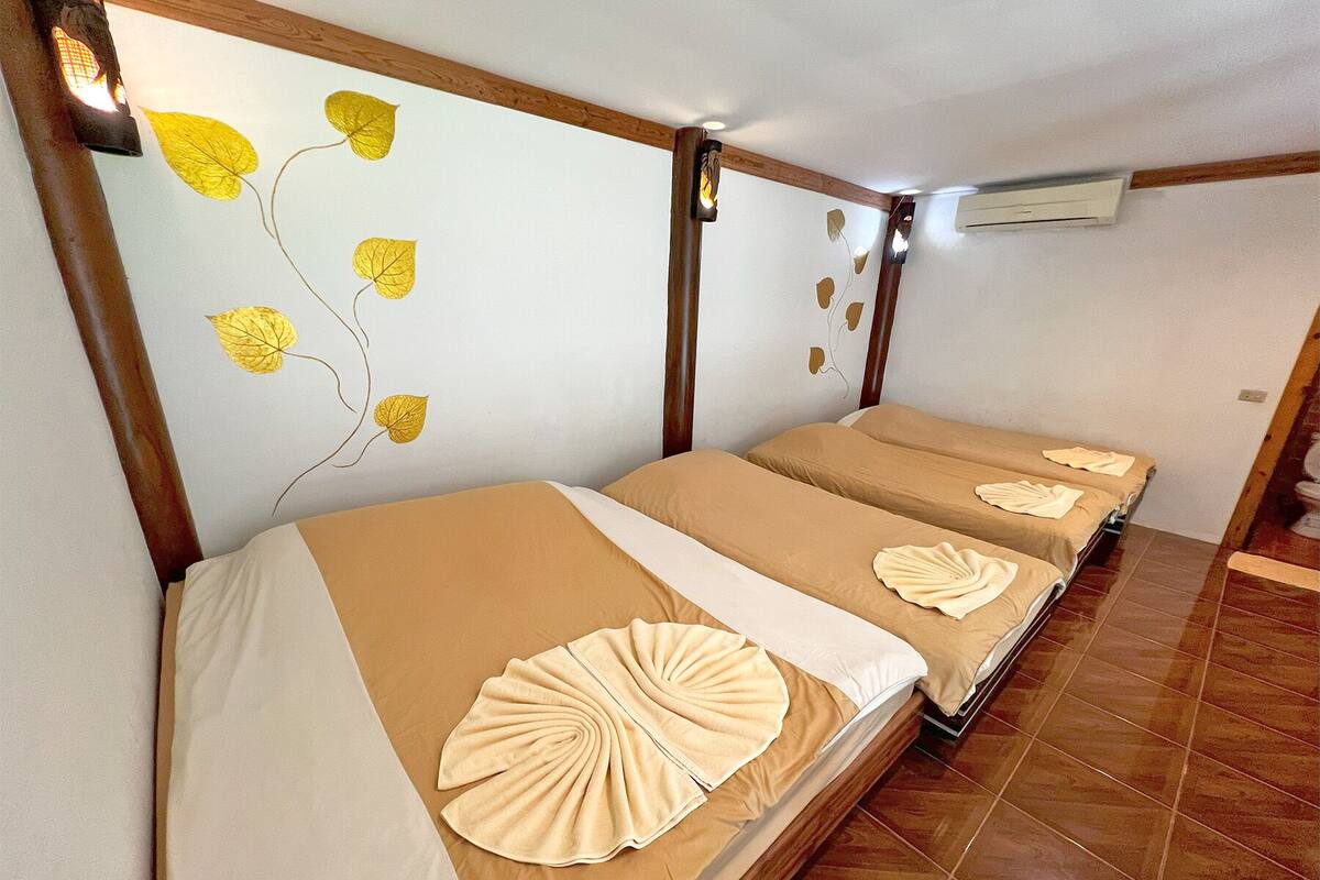 Ein Hotelzimmer mit zwei Betten, jeweils mit einer beigen Tagesdecke und einem dekorativen weißen Kopfkissen.