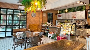 A cozy cafe with a brick wall, a wooden table, and a hanging plant decoration. - Phuiyara Resort Nakhonnayok (Nakhon Nayok)