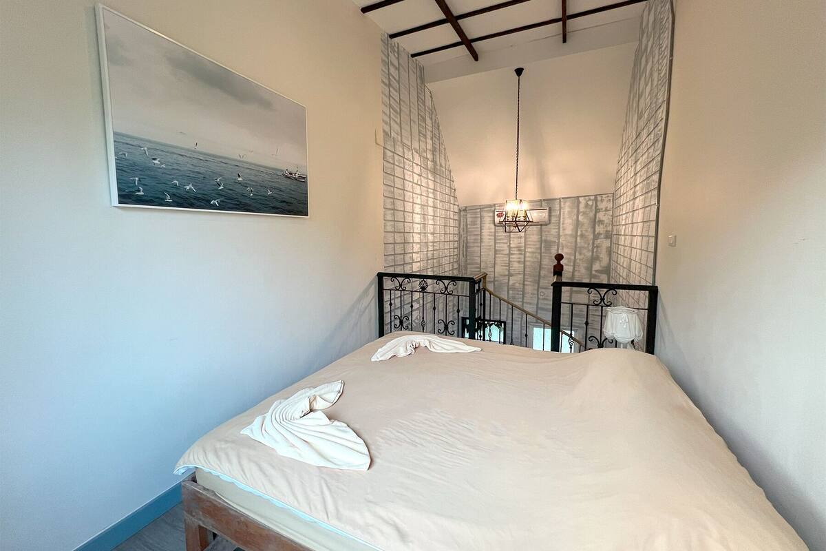 Ein Schlafzimmer mit Bett, einem Gemälde, einer Chandelieber und einer Treppe.