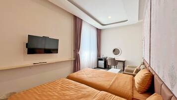 Una habitación de hotel con dos camas, una televisión, un escritorio con una silla y un espejo en la pared.