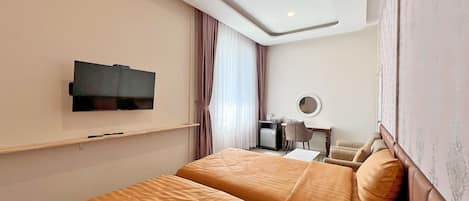 Una habitación de hotel con dos camas, una televisión, un escritorio con una silla y un espejo en la pared.
