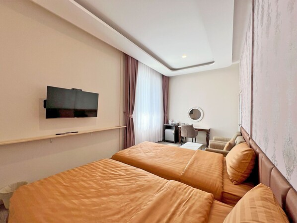 Una habitación de hotel con dos camas, una televisión, un escritorio con una silla y un espejo en la pared.