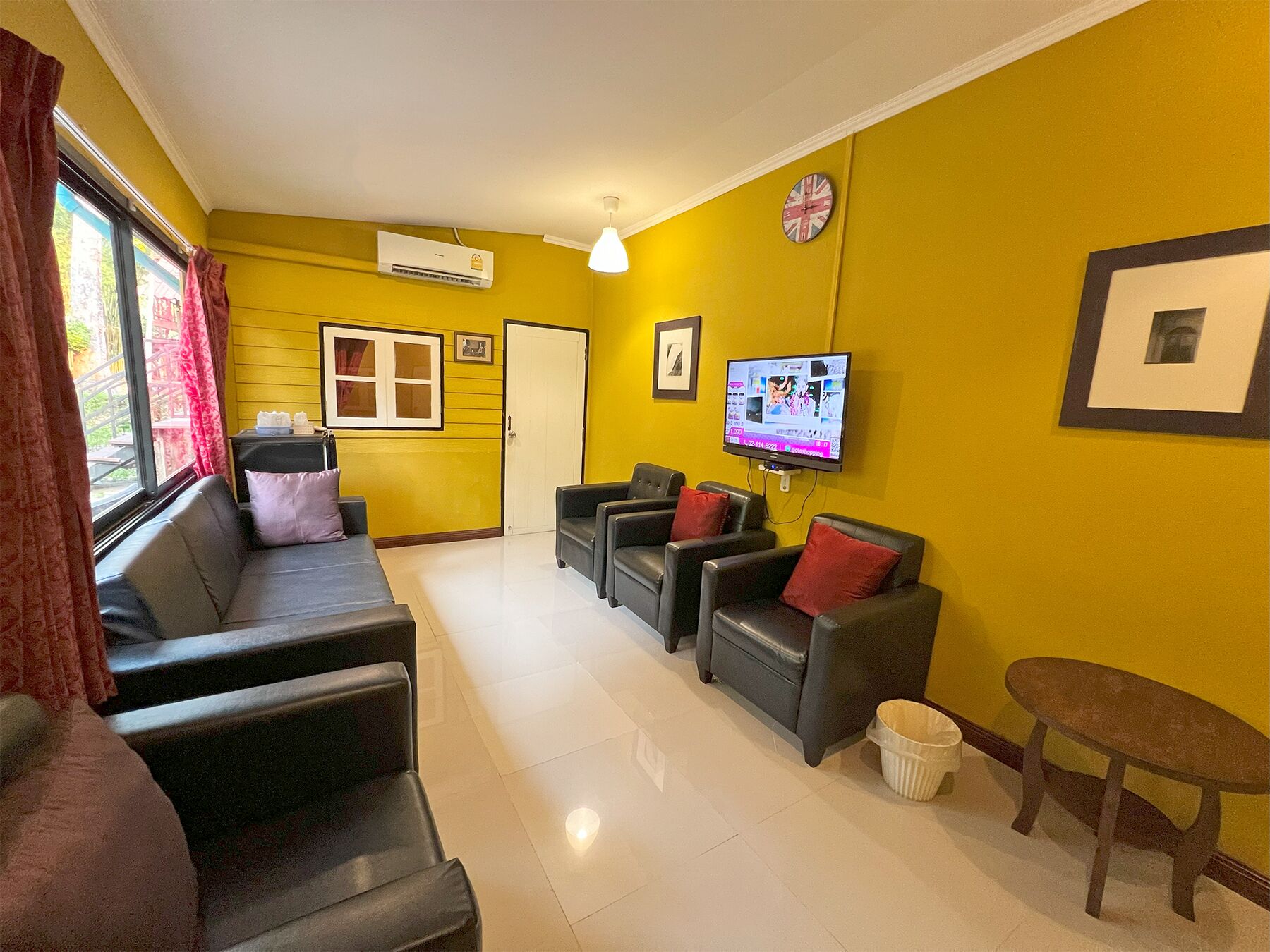 A living room with a sofa, two armchairs, a TV, and a small table.
