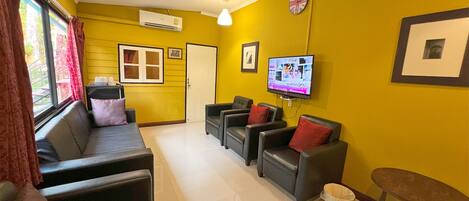 A living room with a sofa, two armchairs, a TV, and a small table.