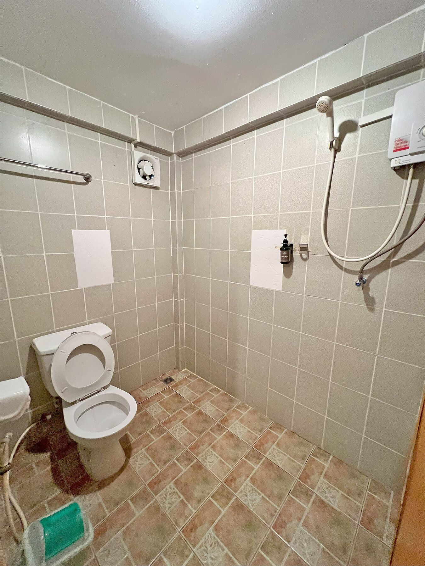 A bathroom with two toilets, a shower, and a hand dryer.