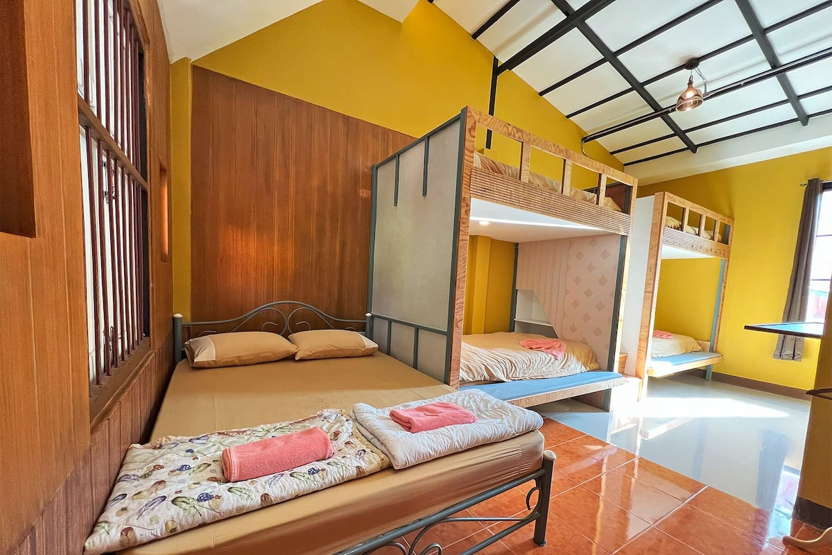 Ein Zimmer mit zwei Etagenbetten, Holzboden und einer gelben Wand.