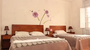 A hotel room with two beds, wooden headboards, bedside tables with lamps, and a wall decoration of flowers and butterflies. - Hotel El Rinconcito Acogedor (Santiago)
