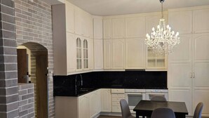 A modern kitchen with white cabinetry, a black countertop, a dining table with chairs, and a chandelier. - H21A-Central-Cozy Spacious Suits family-3 rooms (Oslo)