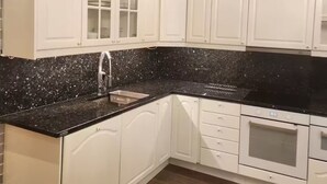 A kitchen with white cabinets, a black granite countertop, and a built-in oven. - H21A-Central-Cozy Spacious Suits family-3 rooms (Oslo)