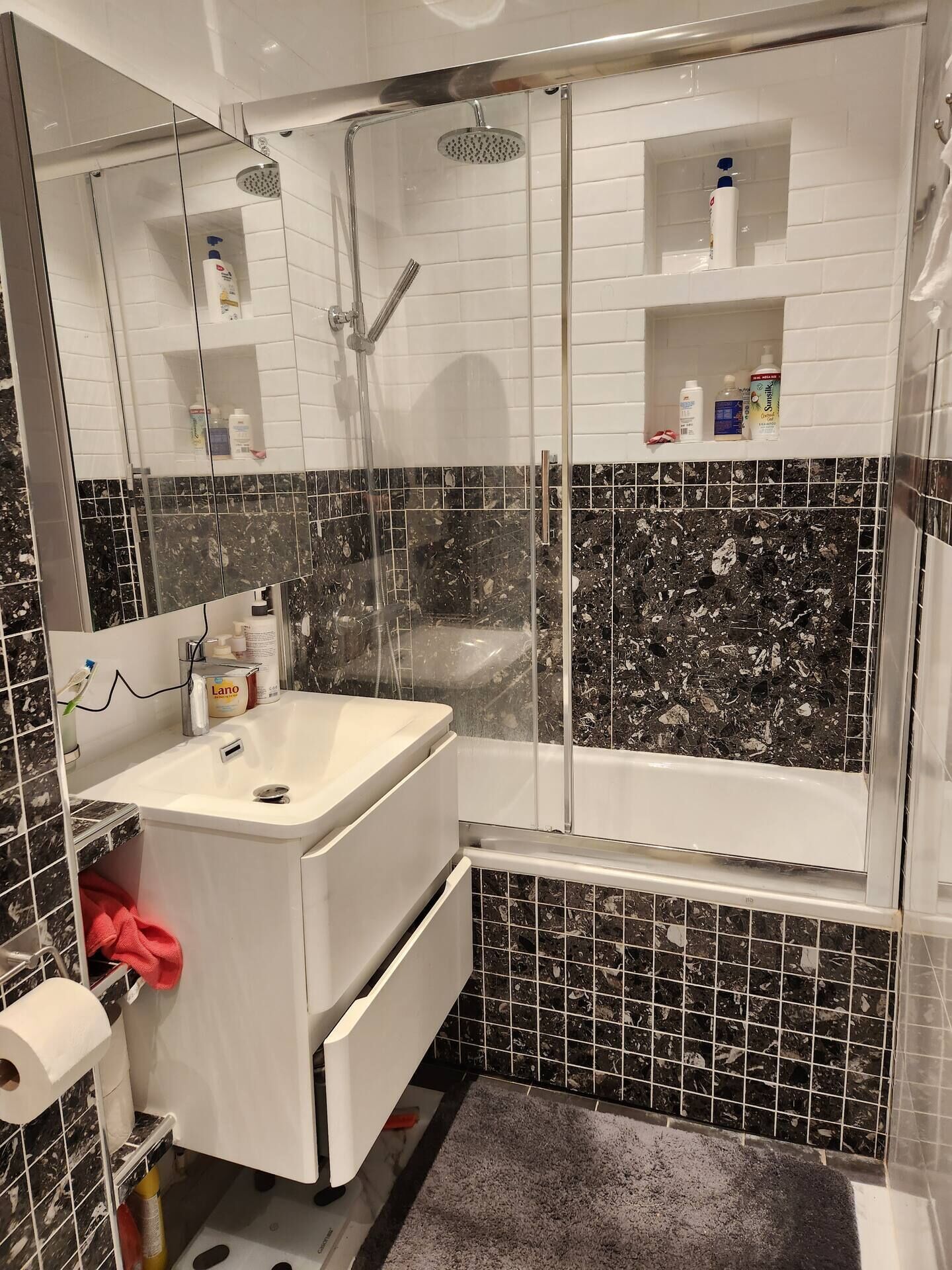 Un baño con un lavamanos blanco, un espejo, cabina de ducha y bañera.