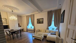 Uma sala de estar moderna com área de jantar, um sofá branco, uma mesa de centro e um candelabro.