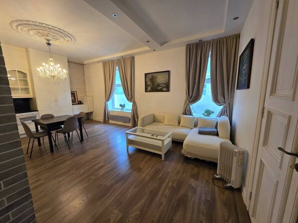 A modern living room with a dining area, a white sofa, a coffee table, and a chandelier.