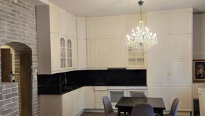 Cozinha moderna com armários brancos, bancada preta e área de refeições com mesa e cadeiras.