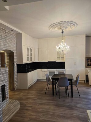 Una cocina moderna con armarios blancos, encimera negra y un comedor con mesa y sillas.