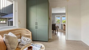 A room with a wicker sofa, a green wardrobe, a dining table with chairs, and a view of the outdoors. - Delightful 2-bedroom apartment in charming Lillehammer (Innlandet)