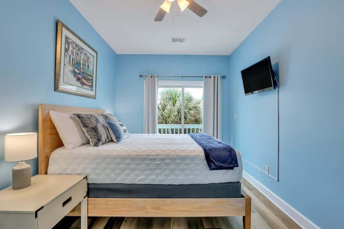 A bedroom with a bed, bedside table, and a TV mounted on the wall.