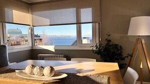 Un comedor con una mesa dispuesta para dos, vista al mar y una lámpara en la esquina.