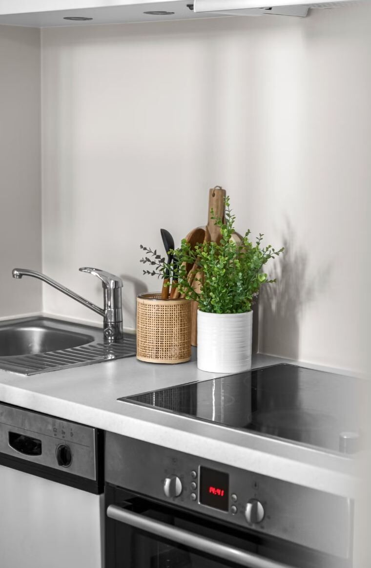 A kitchen with a stainless steel sink, a built-in oven, and a digital clock displaying the time.