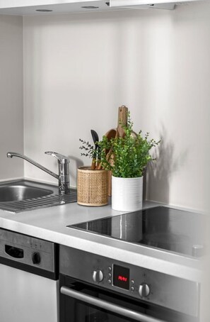 A kitchen with a stainless steel sink, a built-in oven, and a digital clock displaying the time.