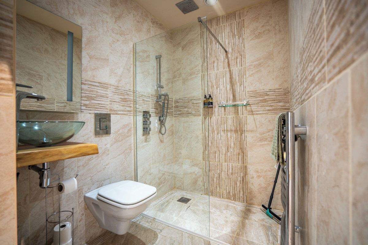 A modern bathroom with a glass-enclosed shower, a white toilet, and a marble-tiled floor.