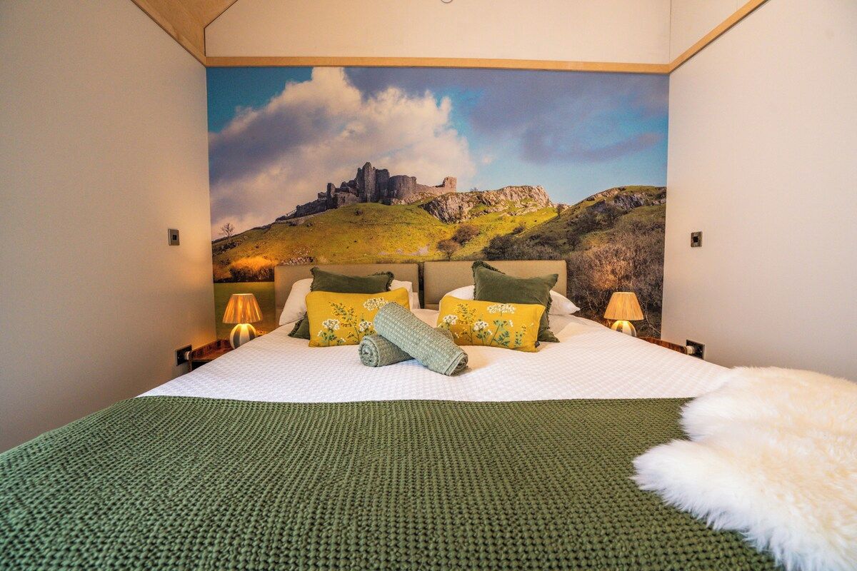 A bedroom with a bed, pillows, a blanket, and a wall mural.