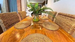 Un coin repas avec une table en bois, des chaises en osier et un vase rempli de fleurs.