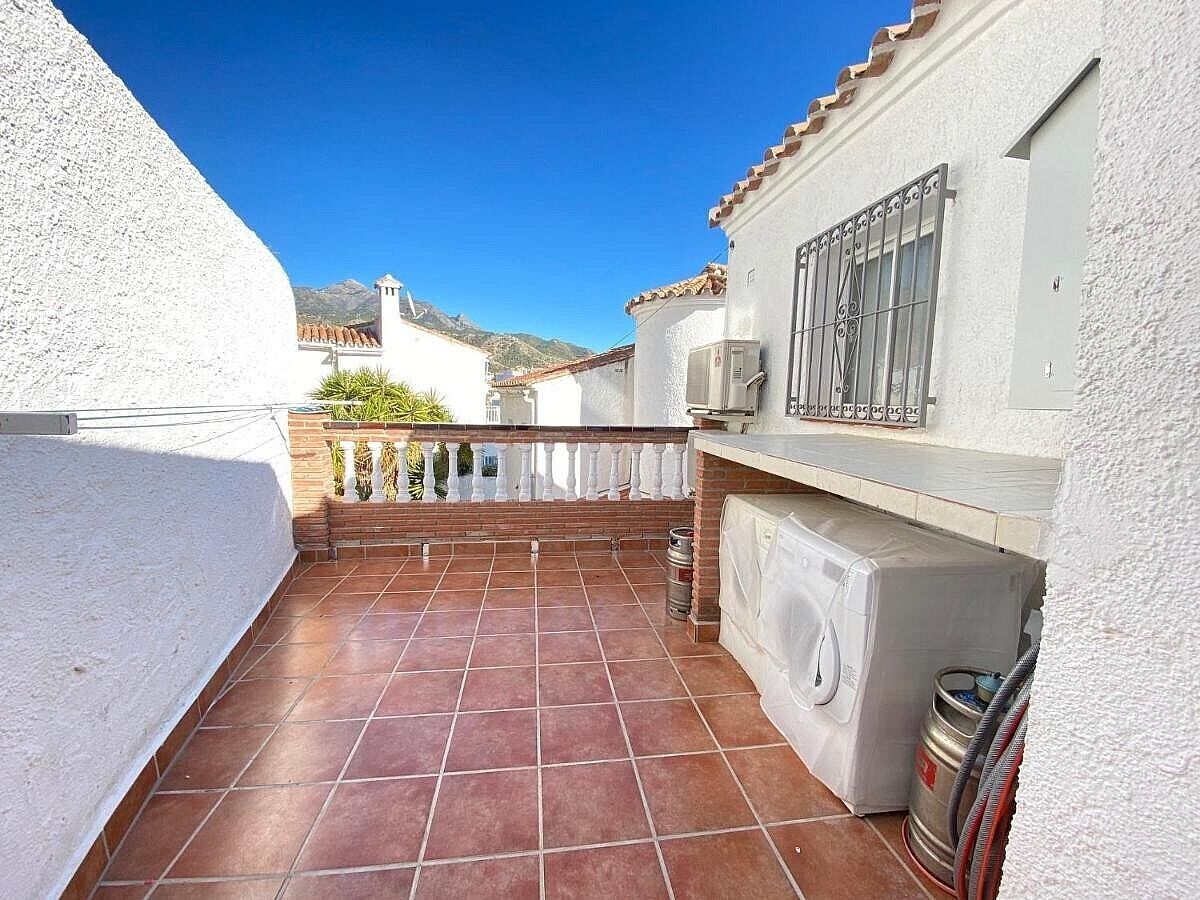 Un petit patio clos, doté d’un sol carrelé, d’un lave-linge et d’une rambarde en métal.