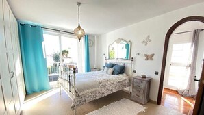 Une chambre à coucher avec un lit, une table de chevet et une fenêtre avec des rideaux.