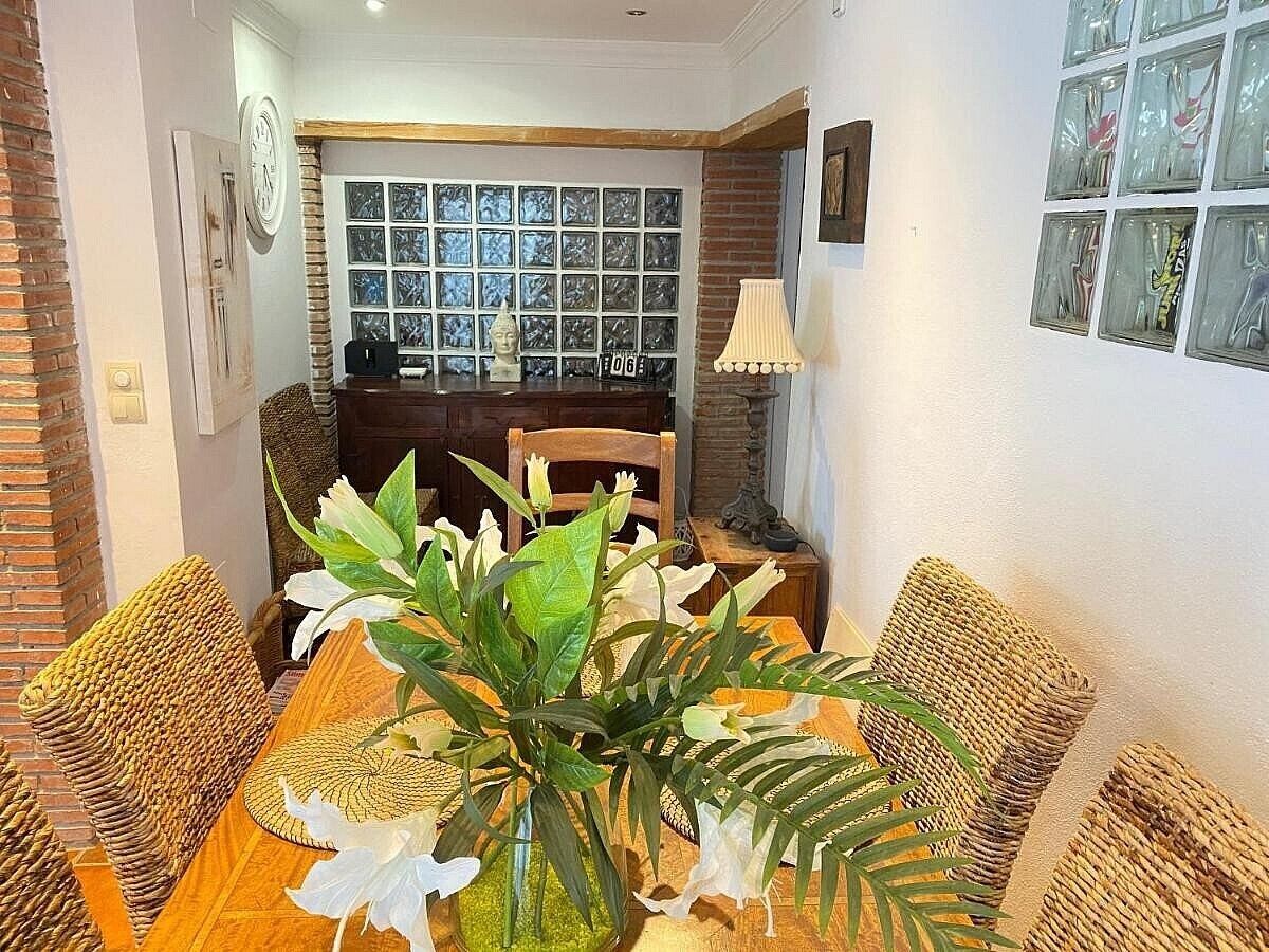 Un coin repas avec une table en bois, des chaises en osier et une plante en pot.