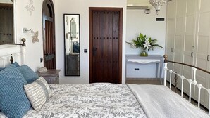 Une chambre à coucher avec un lit, une armoire, un miroir et un lustre.