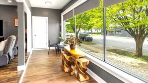 Un interior moderno con comedor, ventanas amplias y vista a la calle.
