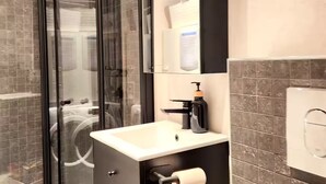 A modern bathroom with a glass-enclosed shower, a white sink with a black faucet, and a large mirror. - P1-Central-Cosy flat Suit All Globetrotters-2rooms (Oslo)