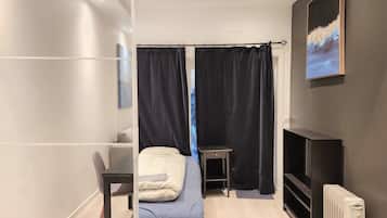 Et moderne soveværelse med seng, skrivebord, stol, radiator og et billede på væggen.