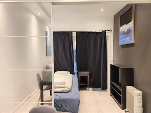 Et moderne soveværelse med seng, skrivebord, stol, radiator og et billede på væggen.