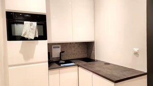 A compact kitchen with white cabinetry, a black oven, and a tiled backsplash. - P1-Central-Cosy flat Suit All Globetrotters-2rooms (Oslo)