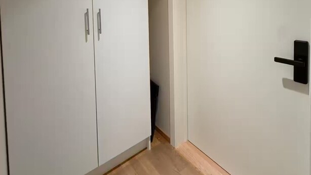 Una stanza con un armadio, una porta e un pavimento in legno.