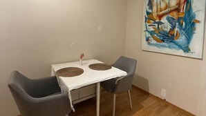 Un'area pranzo con un tavolo, due sedie, una tovaglia bianca e un quadro appeso al muro.