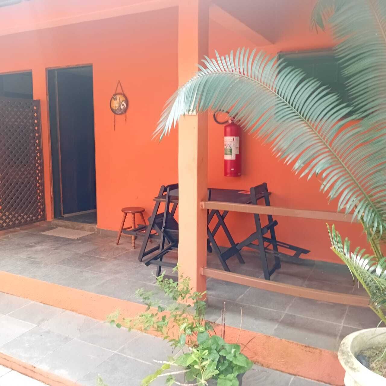 An outdoor seating area with tables and chairs, a fire extinguisher on the wall, and a palm tree.