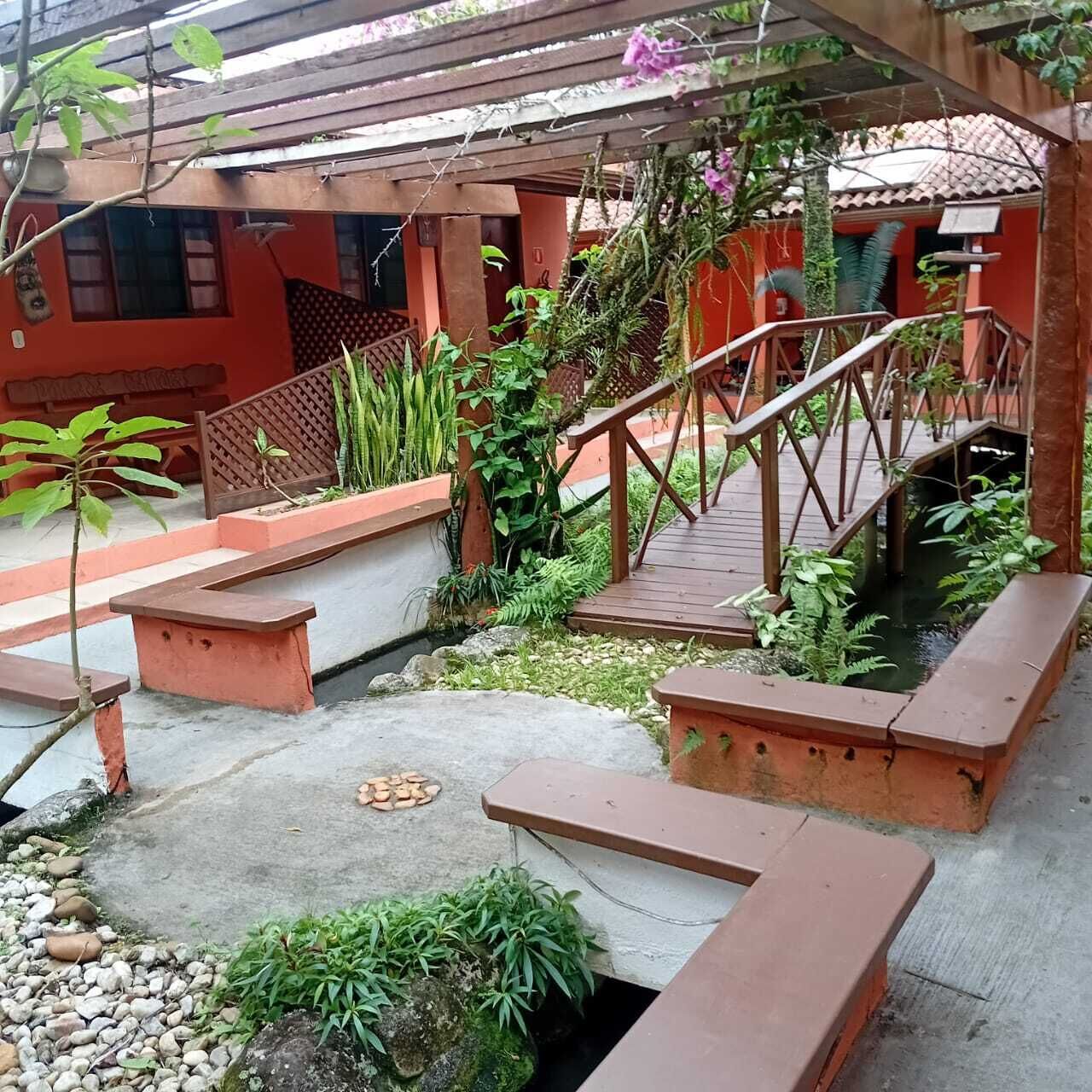 A covered outdoor area with a wooden bridge, benches, and a small water feature.