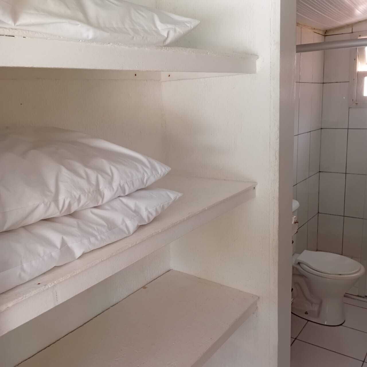 Una habitación con paredes blancas, una zona de ducha con azulejos y un inodoro.