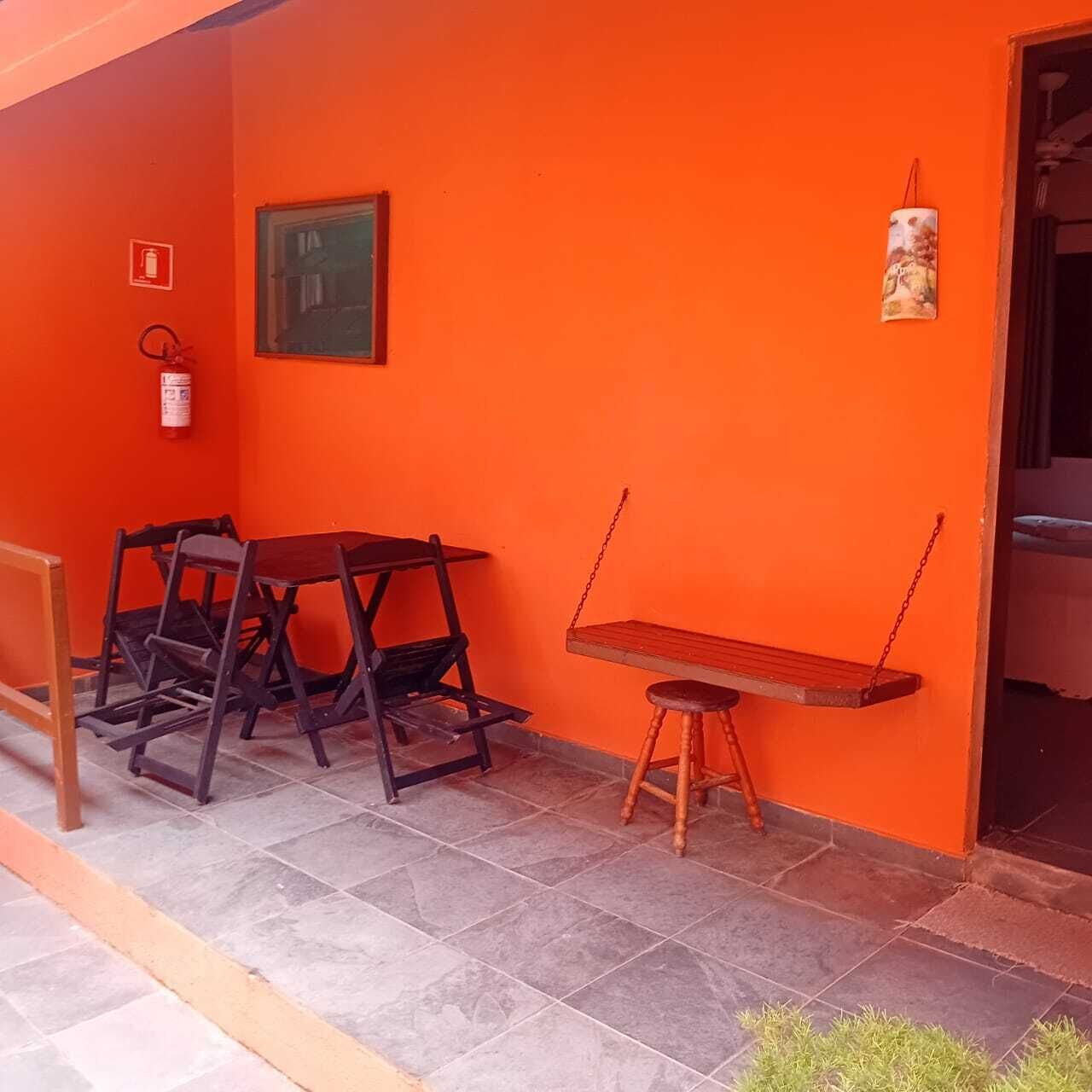 An outdoor seating area with a table and chairs, a swing, and a fire extinguisher on the wall.