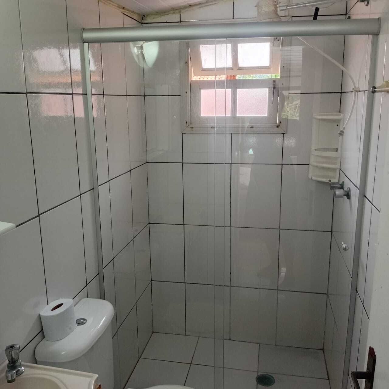 A small, tiled bathroom with a toilet, sink, and shower area.