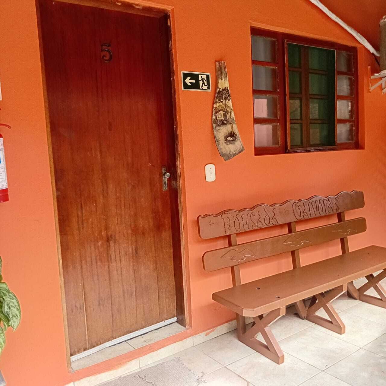 A room with a wooden door, a bench, a window with frosted glass, and a wall-mounted sign.